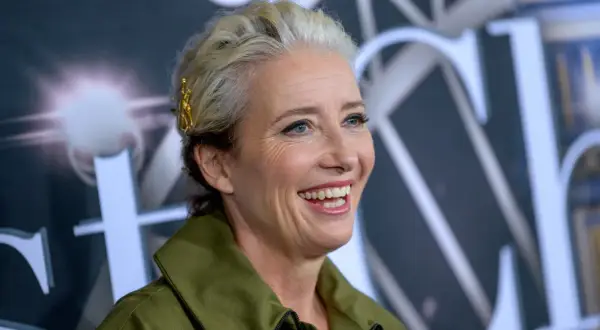 Uśmiechnięta Emma Thompson, znana z wielu wspaniałych filmów, z blond włosami ozdobionymi złotą spinką.