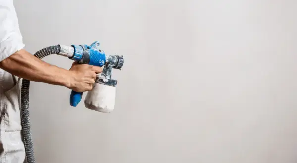 Main tenant, prêt à peindre. Le pistolet à peinture, avec son réservoir rempli, attend la dilution parfaite pour un travail impeccable.