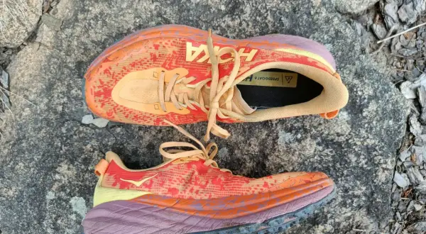 Kolorowe buty Hoka Speedgoat 6 na kamieniu. Hoka to firma znana z amortyzacji i komfortu.