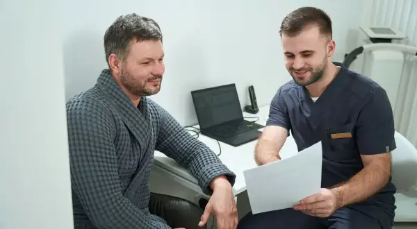 Lekarz omawia wyniki badania urologicznego mężczyzn z pacjentem w szlafroku.
