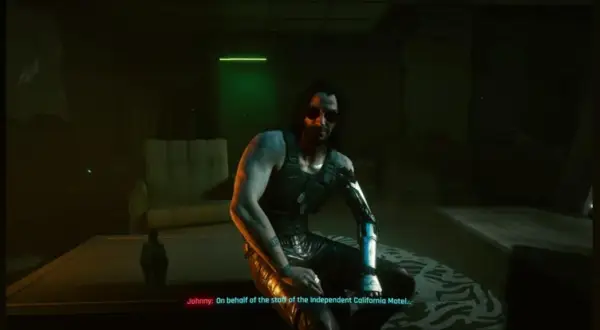 Johnny Silverhand z Cyberpunk 2077 w mrocznym pokoju, z cybernetycznym ramieniem i w okularach przeciwsłonecznych.