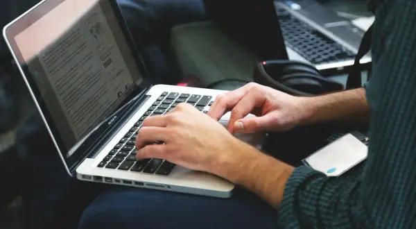Osoba pisze na laptopie, szukając informacji, jak zmienić rozszerzenie pliku.