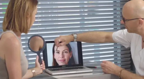 Lekarz pokazuje pacjentce na laptopie zdjęcie twarzy, analizując skórę.