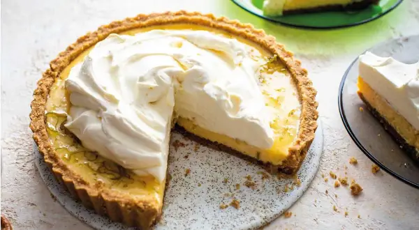 En krämig key lime pie med fluffig grädde på toppen, en bit serverad på en grön tallrik.