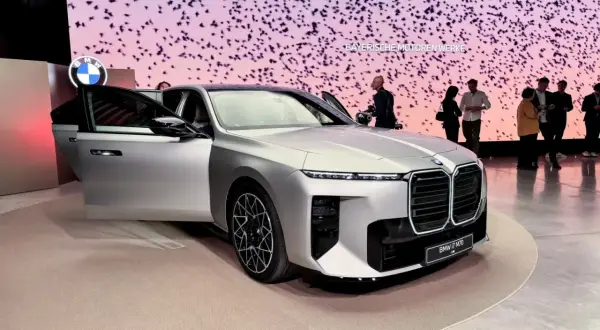 Srebrne BMW serii 7 z otwartymi drzwiami na tle ekranu z ptakami.