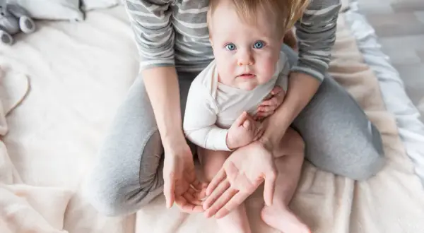Niebieskooki maluch siedzi na kolanach mamy. Zastanawiamy się, ile czasu po uderzeniu w głowę dziecko nie może spać, gdy jest tak czujne.