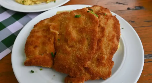 Zwei goldbraune Schnitzel auf einem Teller, garniert mit Schnittlauch. Ein Klassiker der Berliner Küche, der Appetit macht.