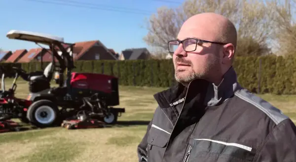 Mann mit Brille, der auf Rasenmäher blickt. Neue Wege für Quereinsteiger in Berufe in der Natur.