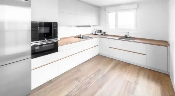 Cocina moderna con armarios blancos y encimeras de madera. Los suelos para cocinas blancas lucen un diseño de madera clara, aportando calidez al espacio.