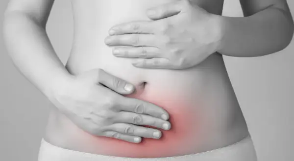 Mani sul ventre con area rossa che indica dolore. L'endometriosi può causare invalidità e sofferenza cronica.
