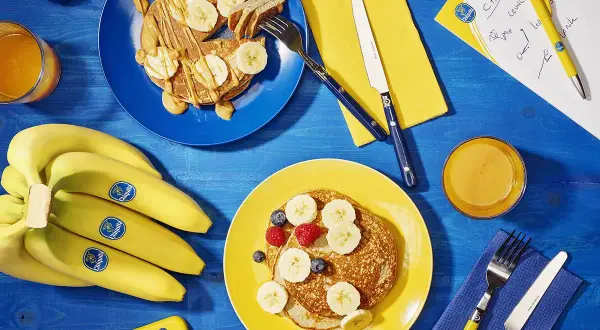 Pancakes con banana dopo allenamento, un pieno di energia. Frutta fresca e succo d'arancia per recuperare al meglio.