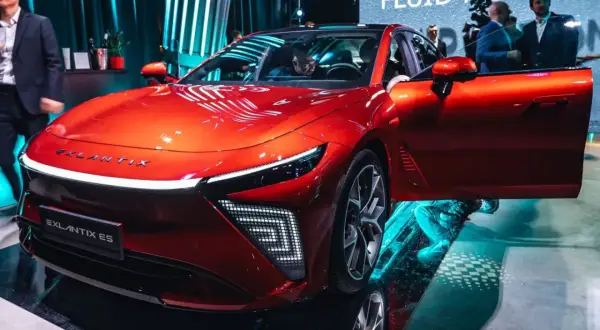 Błyszczący, czerwony Exlantix ES z otwartymi drzwiami, prezentowany na targach. Futurystyczny design i innowacyjne oświetlenie.