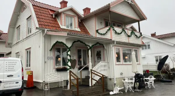 Vitt hus med rosa detaljer och juldekorationer. Skylt visar "Reception Restaurang". Kanske en titt på restaurang Solliden meny?