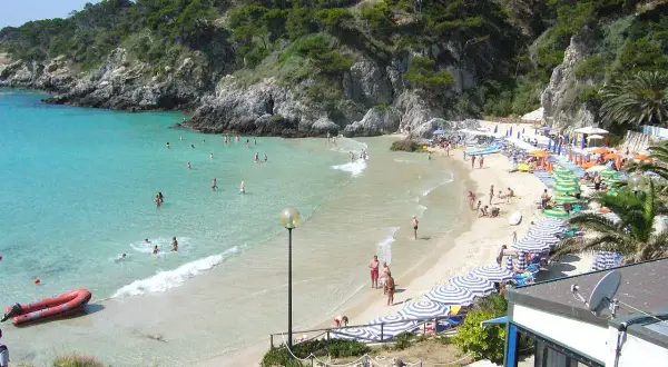 Spiagge delle Isole Tremiti raggiungibili a piedi, con acque cristalline e gente che si gode il sole sotto gli ombrelloni.