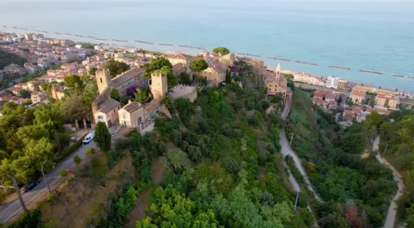 Borgo medievale su una collina affacciata sul mare Adriatico, con il lungomare di Cupra Marittima in lontananza.