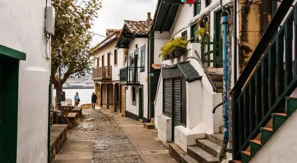 Calle empedrada con casas blancas y balcones de madera, ideal para pasear y descubrir qué ver en Algorta.