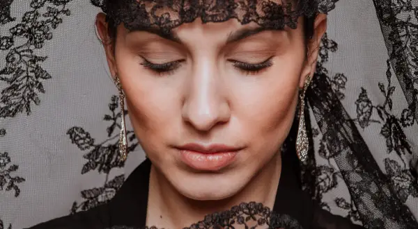 Mujer con peinados de mantilla, luciendo pendientes largos y un abanico de encaje.