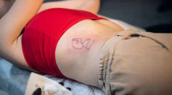 Nowy tatuaż na żebrach, przedstawiający abstrakcyjną postać.