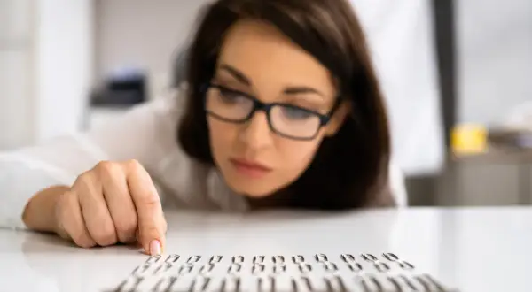 Kobieta w okularach z uwagą układa spinacze, co może sugerować kompulsywne zachowania.