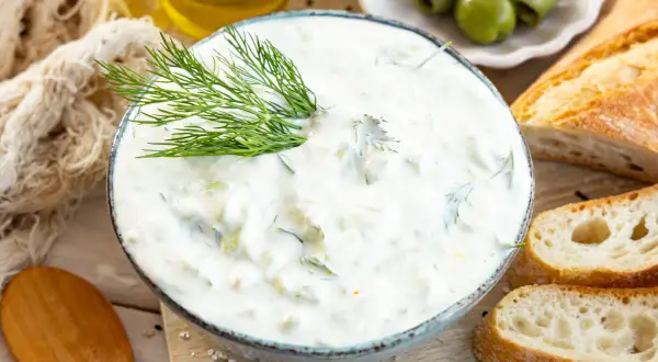 Cremiger Tzatziki mit Dill, serviert mit Baguette und Oliven. Ein einfaches Tzatziki Rezept für den Sommer.