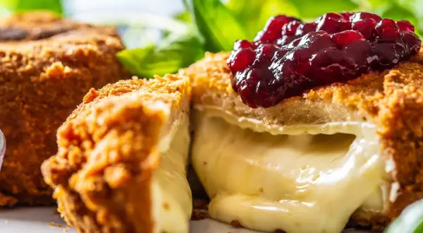Chrupiący camembert w panierce, z rozpływającym się serem w środku, polany konfiturą z owoców leśnych. Idealny na przekąskę.