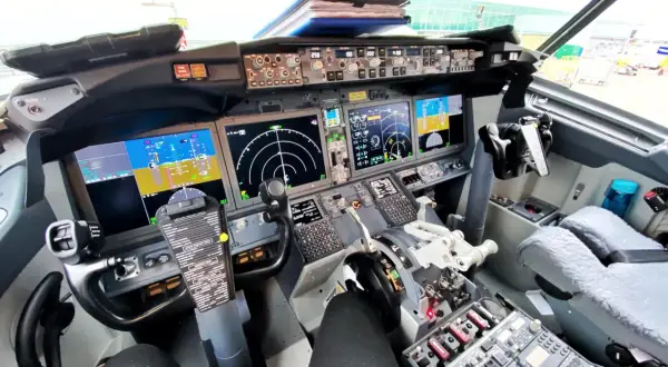 Kokpit samolotu Boeing 737 z widokiem na panele sterowania, ekrany nawigacyjne i yoke.
