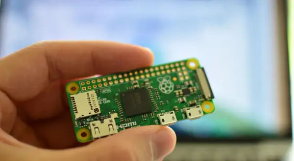 Dłoń trzyma miniaturową płytkę Raspberry Pi Zero W, gotową do projektów. To wszechstronne raspberry pi zastosowanie w elektronice.