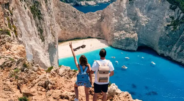 Couple admirant la baie de Navagio, une des plus belles plages des top 5 des îles grecques. L'eau turquoise et les falaises blanches sont spectaculaires.