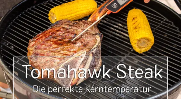 Ein saftiges Tomahawk Steak wird auf dem Grill mit Maiskolben gegrillt. Ein Fleischthermometer misst die Kerntemperatur für das perfekte Ergebnis.
