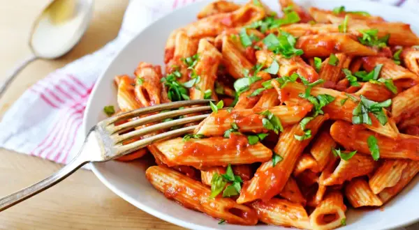 Penne w pikantnym sosie pomidorowym, posypane świeżą bazylią. Idealne spaghetti arrabiata na obiad.