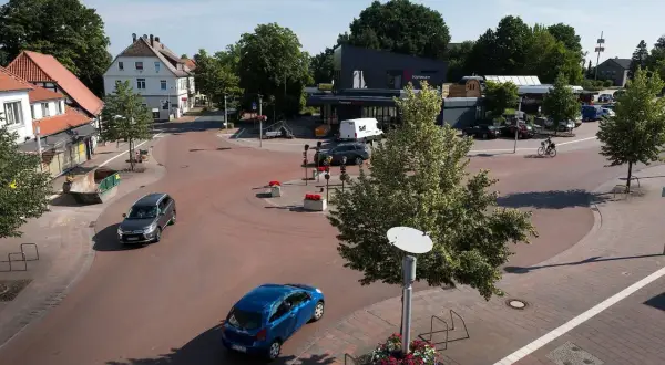 Ein sonniger Tag im **shared space Bohmte**. Autos fahren durch den Kreisverkehr, ein Radfahrer genießt die Fahrt.