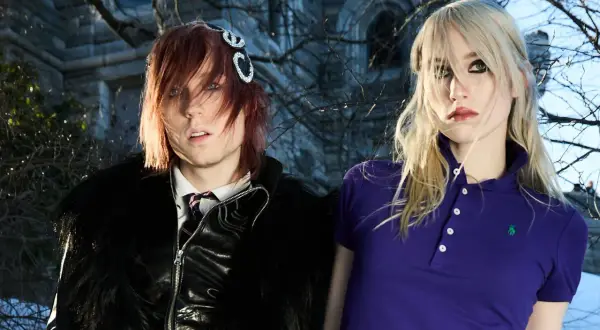 Frost Children setlist: A person with red hair and a black furry jacket stands next to a person with blonde hair in a purple polo shirt.