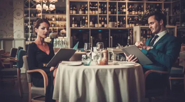 Elegancka para przy stoliku w restauracji, przegląda karty dań. Krótki dialog w restauracji po angielsku, co zamówić?