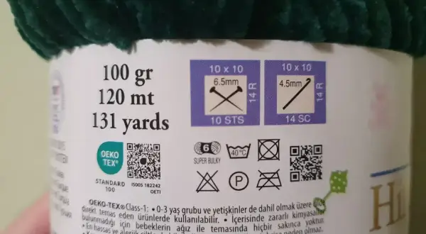 Etykieta z informacjami o różnych rodzajach włóczek: 100g, 120m, 131 jardów. Wskazówki dotyczące rozmiaru drutów i oczek. Certyfikat OEKO-TEX®.