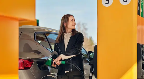 Kvinna tankar sin bil med hvo diesel vid en gul pump.