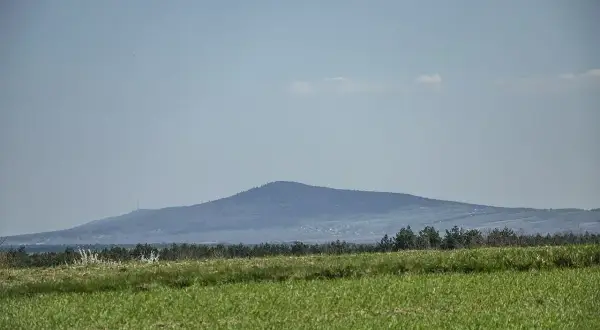 Łagodne, zalesione góry świętokrzyskie szczyty na horyzoncie, z zielonym polem na pierwszym planie.