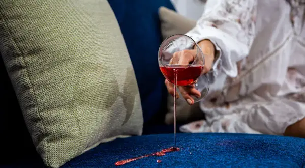 Wino rozlane na granatową kanapę. Jasna poduszka obok, a na niej plamy. Idealne tkaniny obiciowe łatwe do czyszczenia.