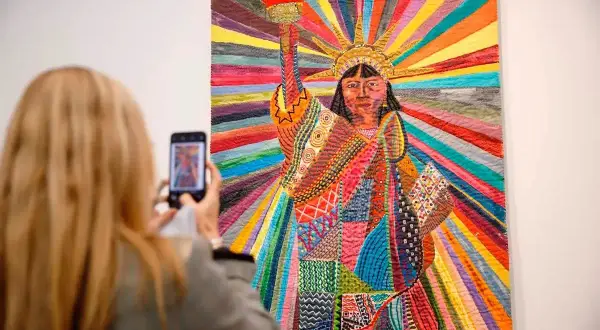 A woman photographs a vibrant quilt depicting the Statue of Liberty, a powerful piece by Asian American artists celebrating diversity.