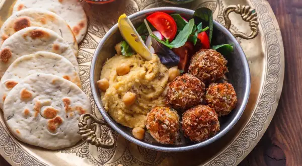 Pyszne jedzenie koszerne: hummus, falafel, świeże pieczywo i sałatka na ozdobnej tacy.