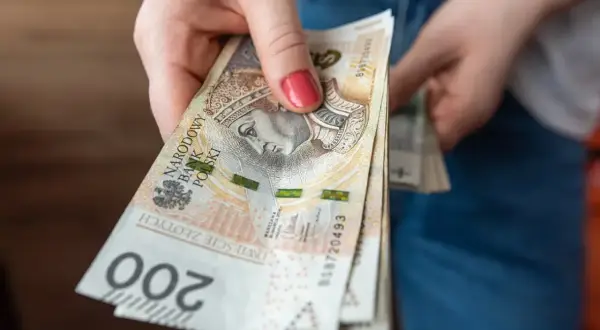 Dłoń trzyma plik banknotów 200 zł. Zastanawiasz się, ile za godzinę pracy?