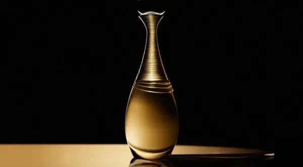 Złota butelka perfum Dior J'adore Infinissime na czarnym tle, emanująca luksusem i elegancją.