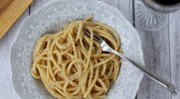 Porcja pysznego cacio e pepe z widelcem w talerzu, gotowa do zjedzenia.