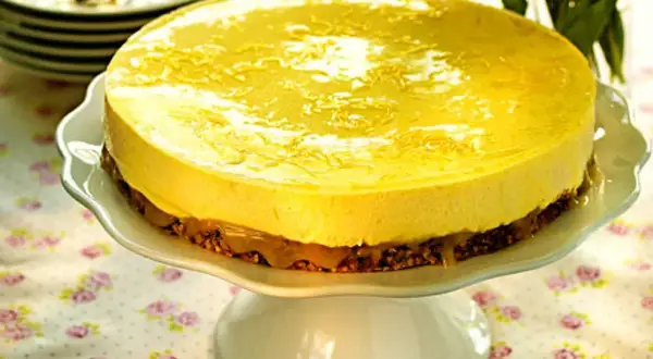 En härlig citronmousse till tårta, med en krispig botten och glansig topping, serveras på ett vackert tårtfat.