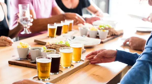 Un gruppo di persone partecipa a un corso degustazione birra, assaggiando diverse varietà accompagnate da stuzzichini.