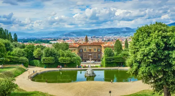 Vista panoramica dei Giardini di Boboli con stagno, palazzo e Firenze sullo sfondo.