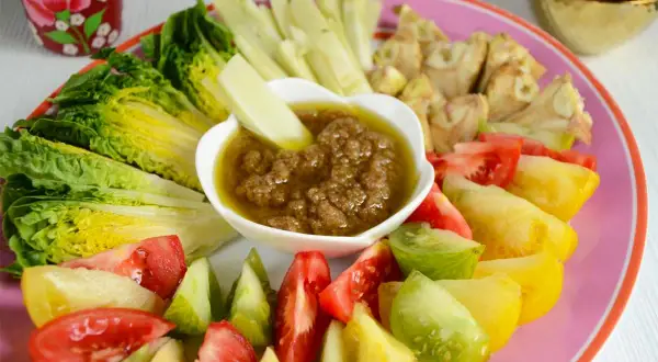Assiette colorée de légumes frais (laitue, tomates variées, céleri) autour d'un bol de bagna cauda.