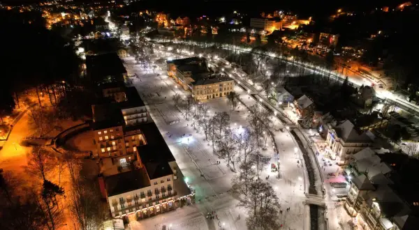 Krynica-Zdrój atrakcje wieczorem: ośnieżony deptak, iluminowane budynki i spacerujący ludzie tworzą magiczny zimowy krajobraz.