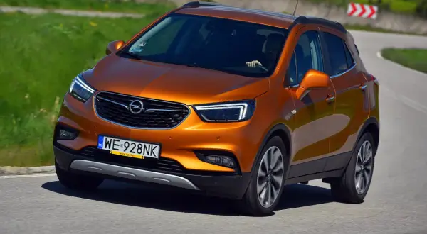 Pomarańczowy Opel Mokka 2015 na zakręcie drogi.