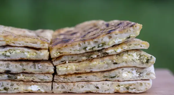 Pile de pains plats au fromage et aux herbes, rappelant l'origine du cheese naan.