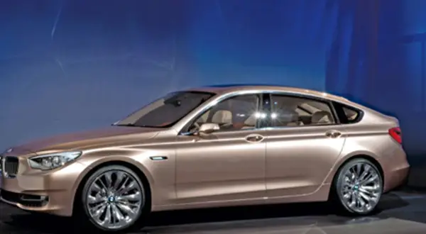 Eleganckie, złociste bmw 5gt z chromowanymi felgami prezentuje się imponująco na tle niebieskiego, świetlistego tła.